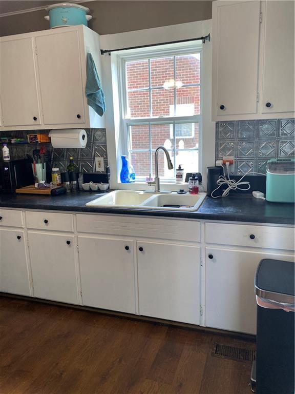 1404 S Barrett Ave, Sedalia, MO 65301 - kitchen with a sink, white cabinetry, backsplash, and dark countertops