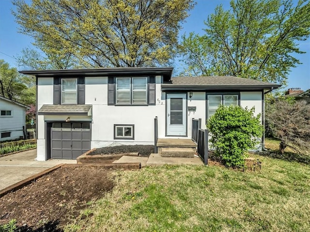tri-level home featuring an attached garage, stucco siding, driveway, and a front yard
