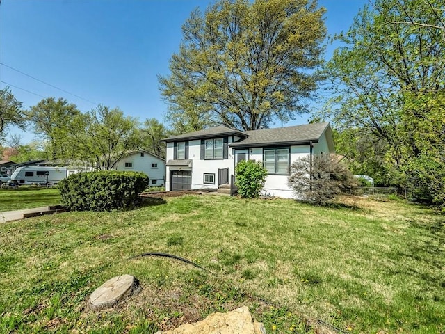 split level home with a garage, a front lawn, and stucco siding
