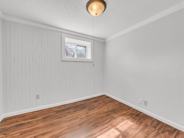 empty room featuring baseboards, a textured ceiling, and wood finished floors