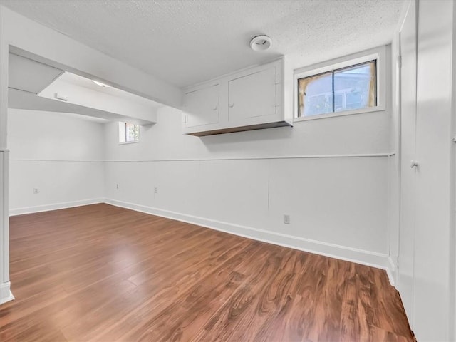 below grade area featuring baseboards, a textured ceiling, and wood finished floors