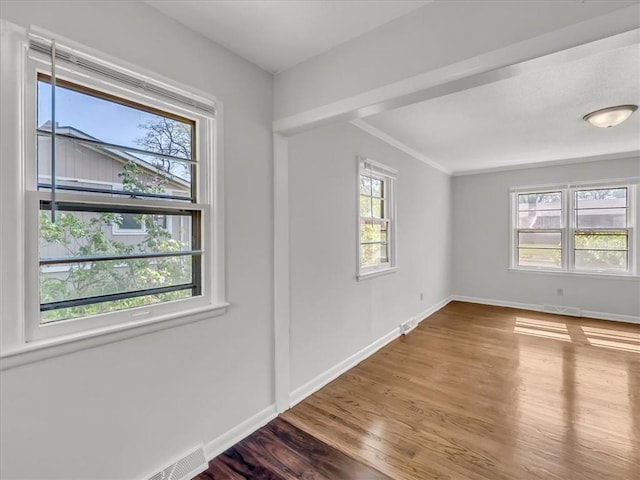unfurnished room featuring baseboards, ornamental molding, wood finished floors, and visible vents