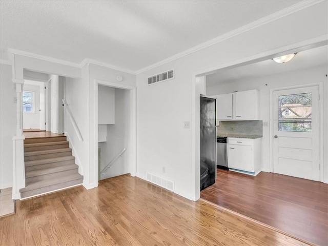 unfurnished living room featuring ornamental molding, wood finished floors, and visible vents