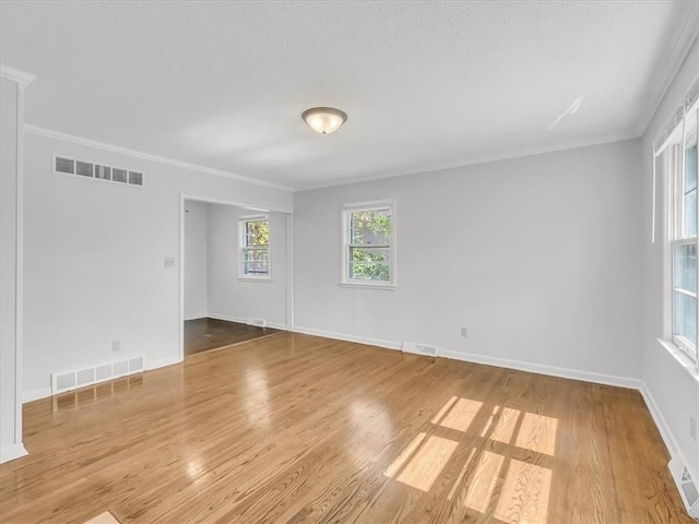 empty room featuring baseboards, visible vents, and wood finished floors