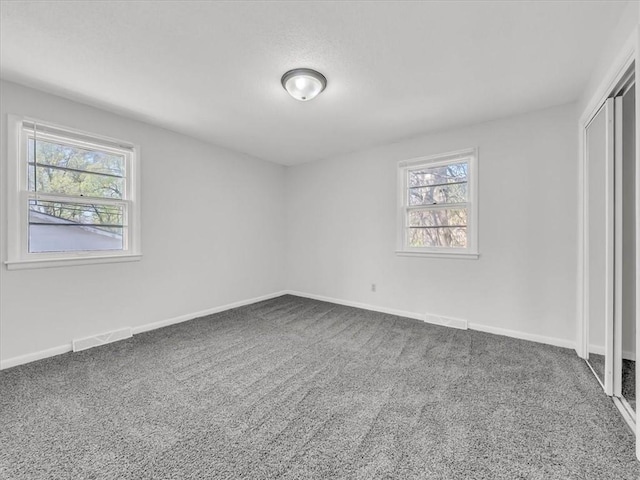 unfurnished bedroom with a closet, carpet, and multiple windows