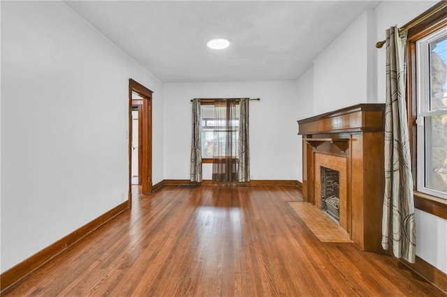 108 N Lawn Ave, Kansas City, MO 64123 - unfurnished living room featuring baseboards, wood finished floors, and a tile fireplace