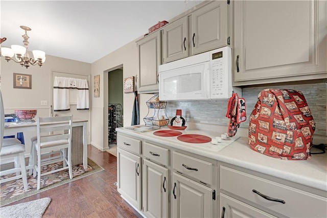 1003 Leone Ave, Sedalia, MO 65301 - kitchen with tasteful backsplash, dark wood finished floors, light countertops, white microwave, and an inviting chandelier