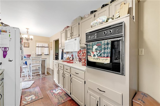 1003 Leone Ave, Sedalia, MO 65301 - kitchen with white appliances, light countertops, a chandelier, decorative backsplash, and wood finished floors