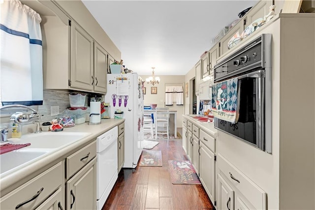 1003 Leone Ave, Sedalia, MO 65301 - kitchen featuring an inviting chandelier, white appliances, light countertops, a sink, and dark wood finished floors