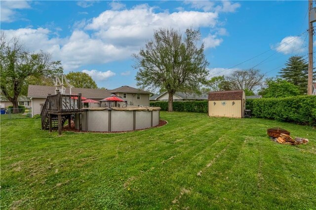 1003 Leone Ave, Sedalia, MO 65301 - view of yard featuring a storage unit, an outdoor fire pit, a deck, a fenced in pool, and an outbuilding