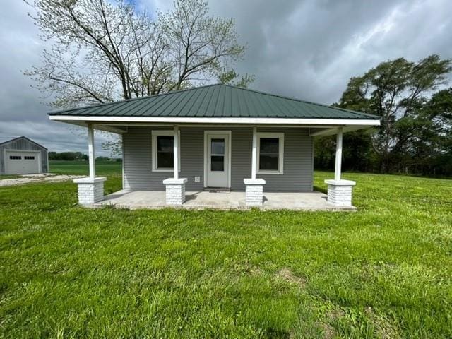 back of house featuring a porch, a yard, and metal roof