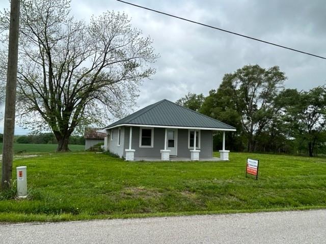 bungalow-style home featuring a front lawn, a porch, and metal roof
