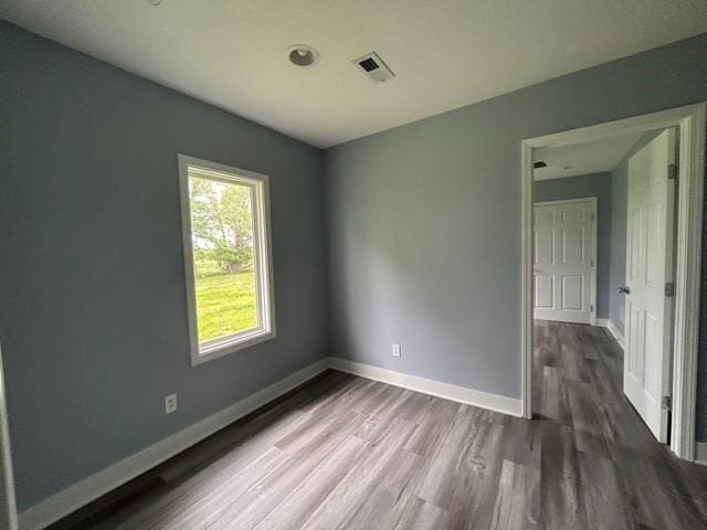 spare room featuring dark wood finished floors and baseboards
