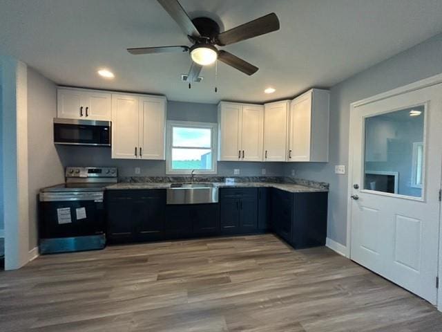 kitchen with appliances with stainless steel finishes, a sink, white cabinets, recessed lighting, and a ceiling fan