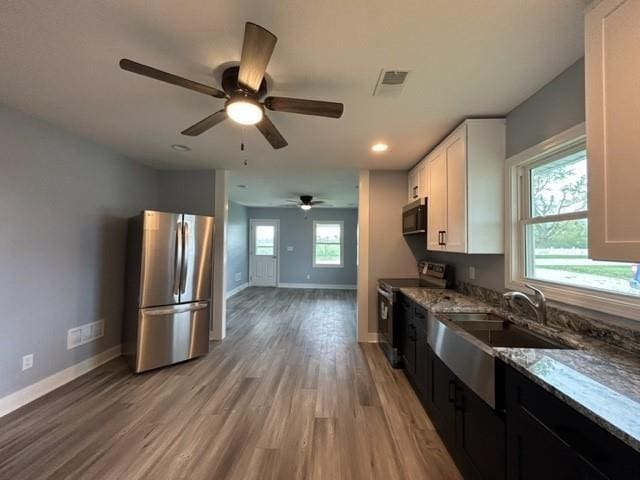 kitchen with stainless steel appliances, light stone counters, baseboards, white cabinetry, and light wood-style flooring