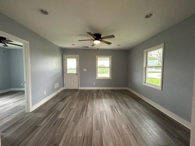 unfurnished living room featuring ceiling fan, dark wood-style flooring, and baseboards