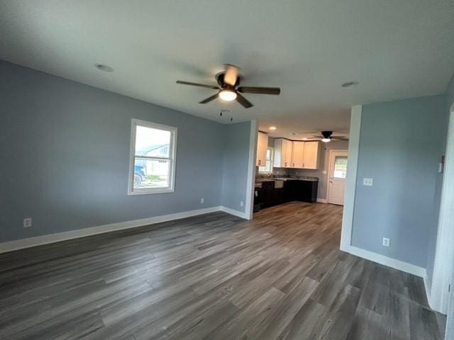 unfurnished living room with ceiling fan, dark wood-style floors, and baseboards