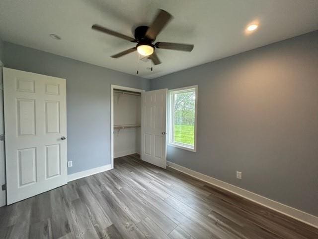 unfurnished bedroom with baseboards, dark wood finished floors, a closet, and ceiling fan