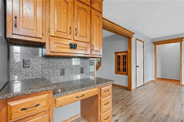 19707 E State Route A, Archie, MO 64725 - kitchen with baseboards, backsplash, light wood-style flooring, dark stone counters, and brown cabinetry