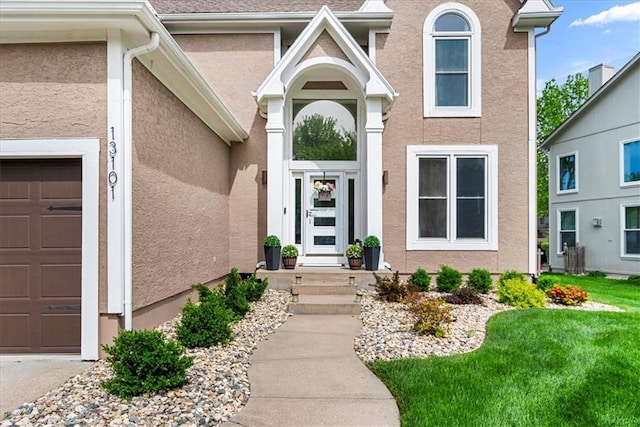 entrance to property featuring an attached garage and stucco siding
