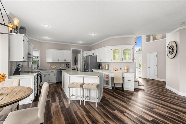 kitchen with ornamental molding, appliances with stainless steel finishes, white cabinets, and dark wood-style floors