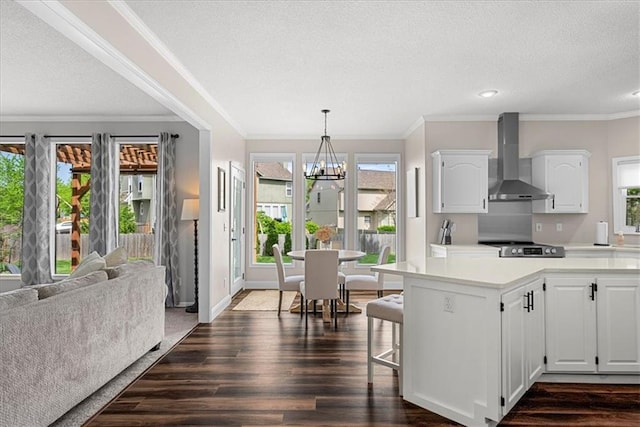 kitchen featuring an inviting chandelier, dark wood-style floors, light countertops, a textured ceiling, and wall chimney exhaust hood