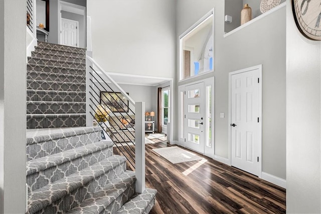 entrance foyer with stairs, a high ceiling, dark wood finished floors, and baseboards
