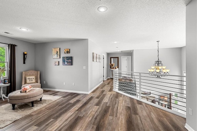 sitting room featuring a textured ceiling, visible vents, wood finished floors, and a notable chandelier