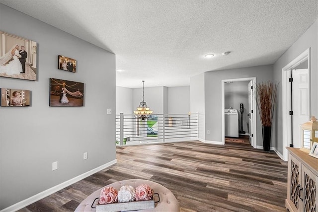 interior space featuring an inviting chandelier, a textured ceiling, wood finished floors, and washer / dryer