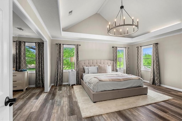 bedroom featuring an inviting chandelier, lofted ceiling, multiple windows, and wood finished floors