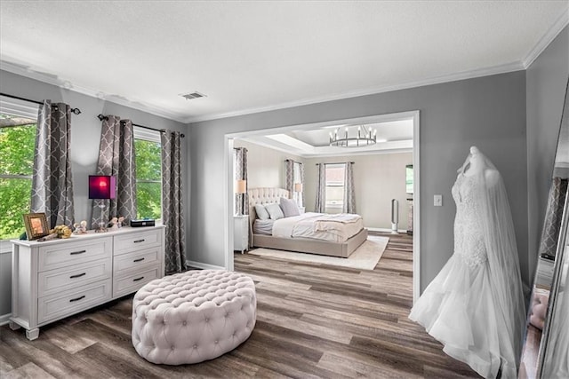 bedroom featuring crown molding, an inviting chandelier, a textured ceiling, wood finished floors, and visible vents