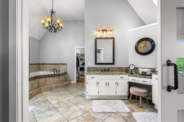 bathroom with high vaulted ceiling, an inviting chandelier, a bath, and vanity
