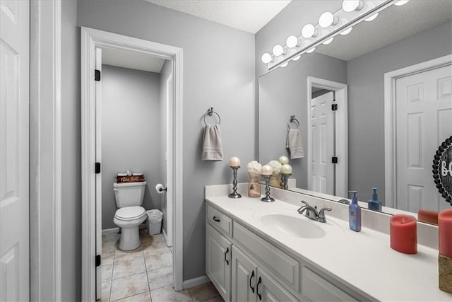 bathroom featuring vanity, toilet, a textured ceiling, tile patterned floors, and baseboards