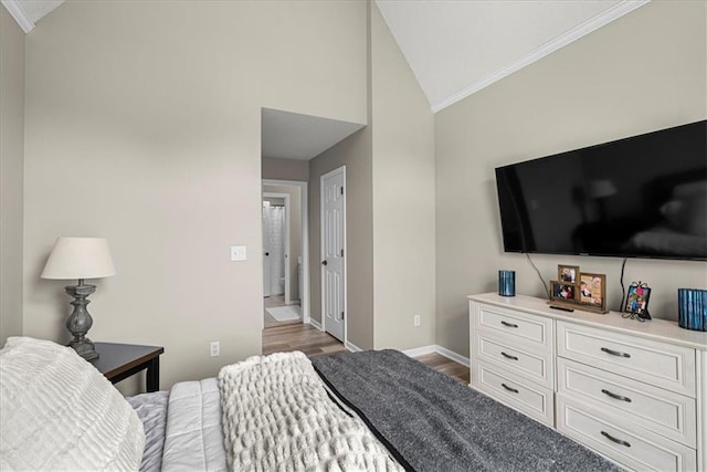 bedroom featuring baseboards, ornamental molding, wood finished floors, and lofted ceiling