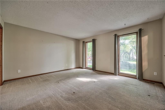 unfurnished room featuring carpet, a textured ceiling, and baseboards