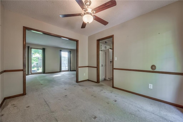 unfurnished room with carpet, ceiling fan, a textured ceiling, and baseboards