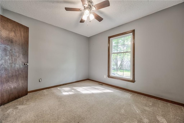 carpeted empty room featuring a textured ceiling, a ceiling fan, and baseboards