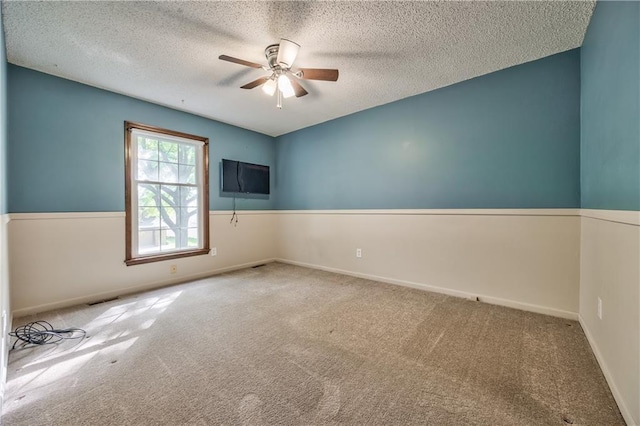 carpeted empty room featuring a ceiling fan, a textured ceiling, and baseboards