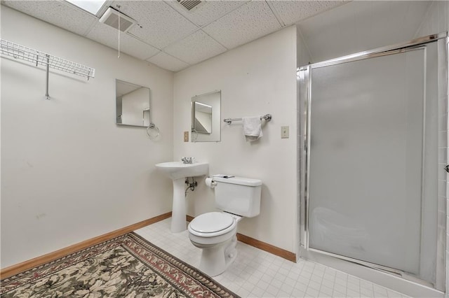 full bath with a stall shower, toilet, a drop ceiling, and baseboards