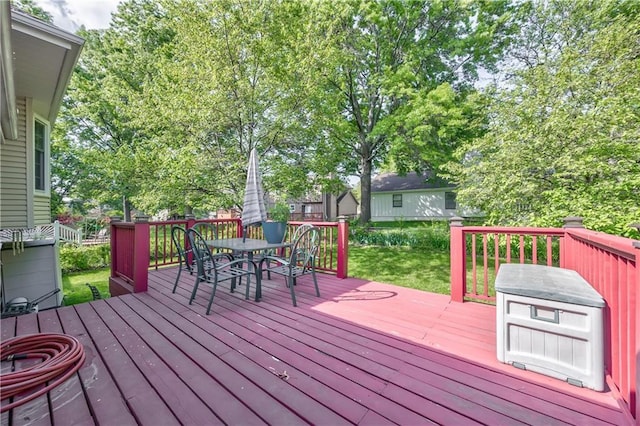 wooden deck featuring outdoor dining area and a lawn