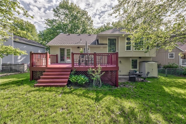 rear view of house featuring a deck, roof with shingles, and a storage unit