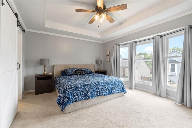 carpeted bedroom with crown molding, baseboards, a barn door, a tray ceiling, and a ceiling fan