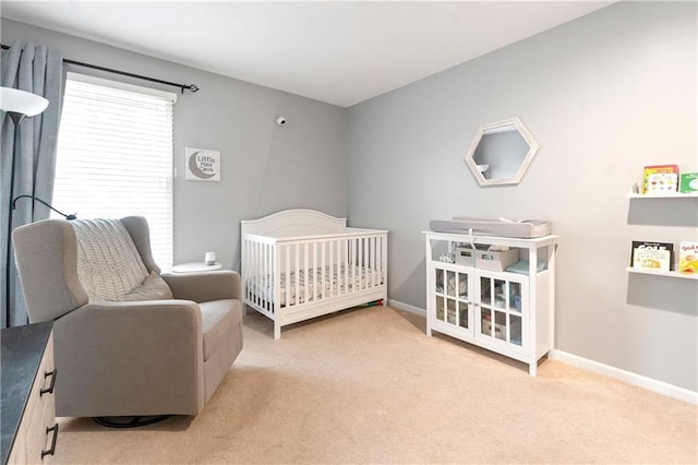 carpeted bedroom with baseboards and a crib