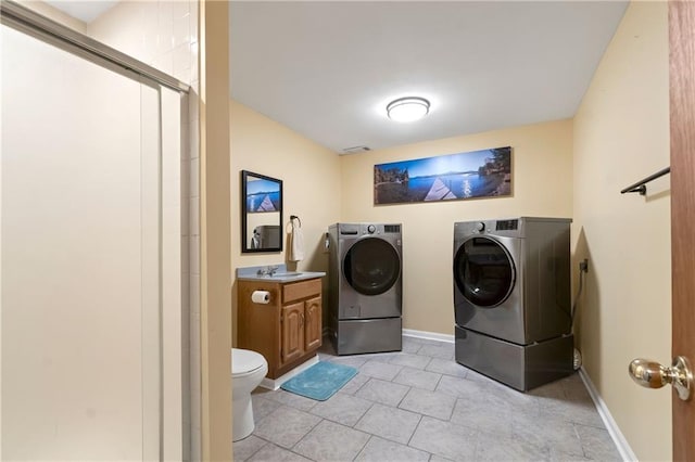 laundry area featuring washing machine and clothes dryer, laundry area, a sink, light tile patterned floors, and visible vents
