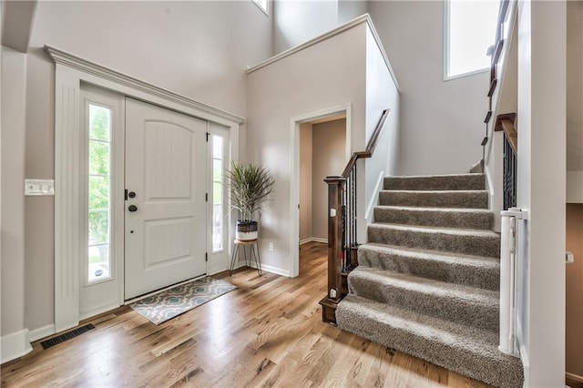 foyer featuring stairs, baseboards, visible vents, and wood finished floors