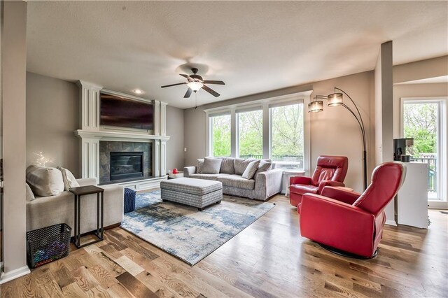 living room featuring ceiling fan, a fireplace, and wood finished floors