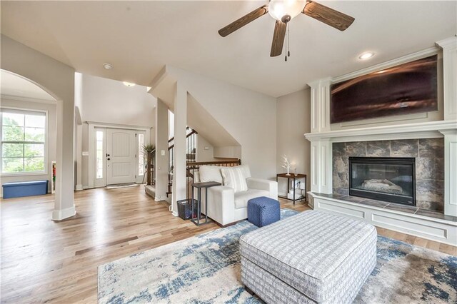 living room featuring light wood-style floors, arched walkways, baseboards, and ceiling fan