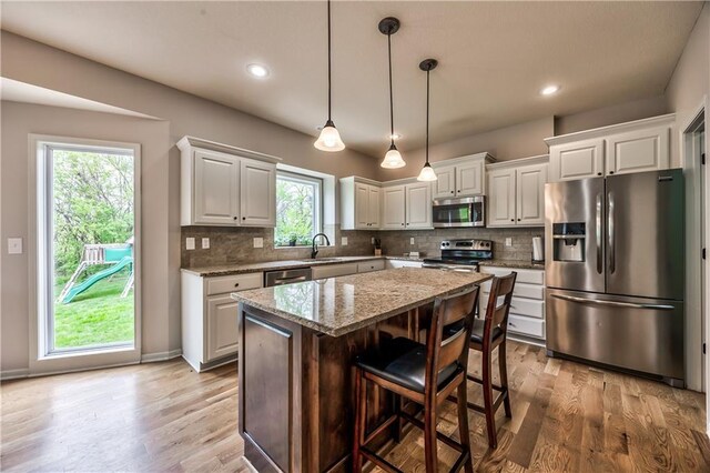 kitchen with light wood-type flooring, appliances with stainless steel finishes, and backsplash