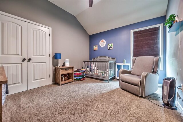 bedroom with a closet, carpet floors, vaulted ceiling, and a crib