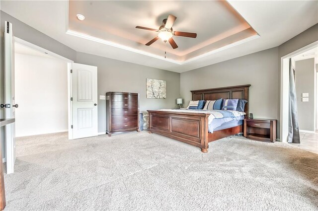 bedroom featuring a ceiling fan, baseboards, light carpet, and a raised ceiling
